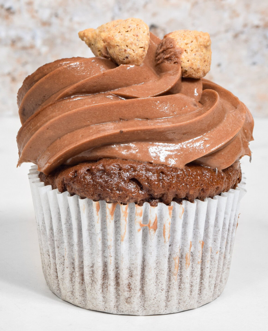 Chocolate cupcake with chocolate frosting and two hazelnut cookies